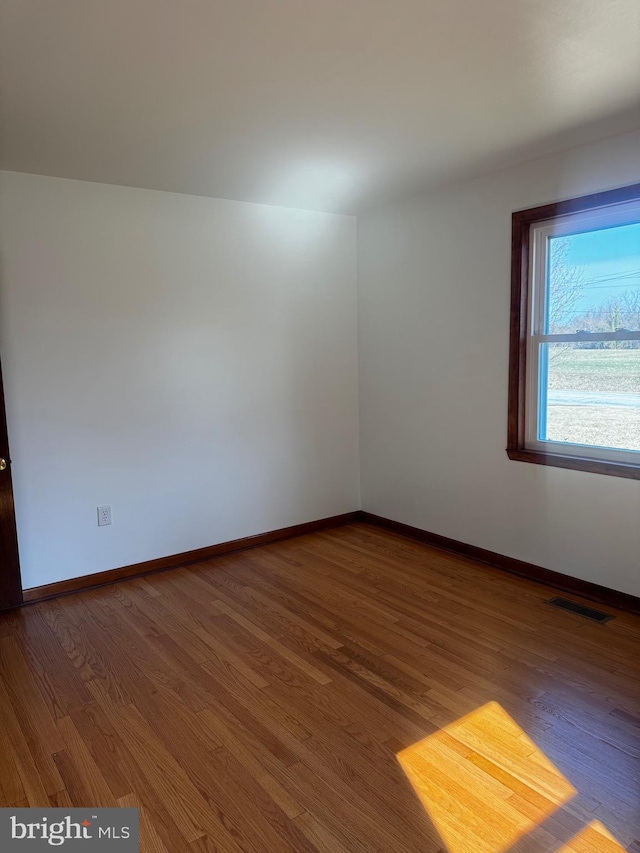 empty room featuring visible vents, baseboards, and wood finished floors