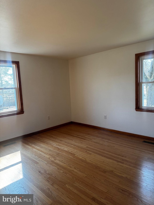 unfurnished room with visible vents, baseboards, and wood finished floors