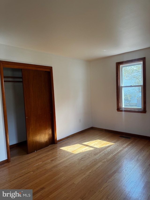 unfurnished bedroom with a closet, baseboards, and wood finished floors