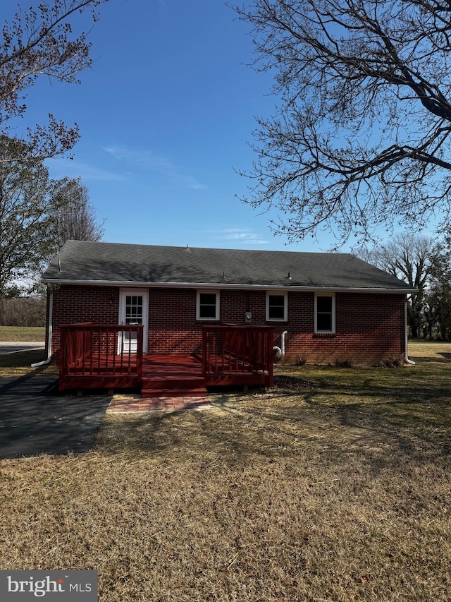 view of front of property with a deck, brick siding, and a front yard