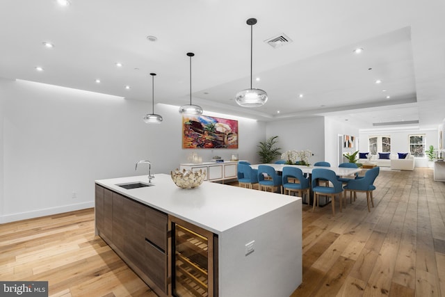 kitchen featuring visible vents, beverage cooler, a sink, a spacious island, and a raised ceiling