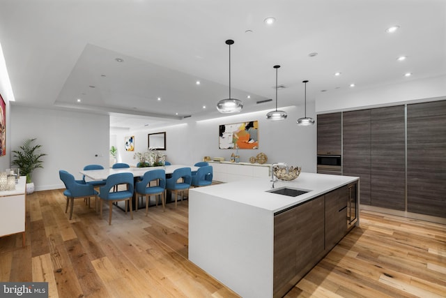 kitchen with a spacious island, light wood-type flooring, a sink, and modern cabinets