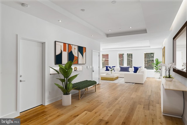 interior space featuring light wood finished floors, a raised ceiling, and recessed lighting