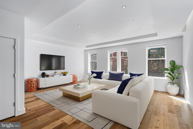 living area featuring light wood-type flooring, baseboards, a tray ceiling, and recessed lighting