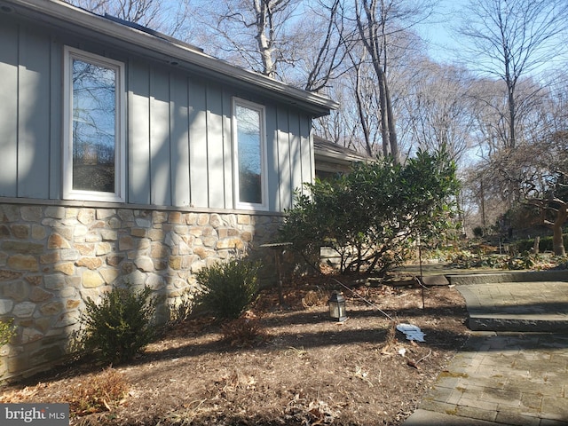 view of side of home featuring board and batten siding and stone siding