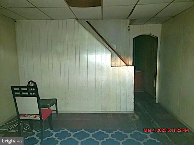 interior space with a paneled ceiling and wooden walls