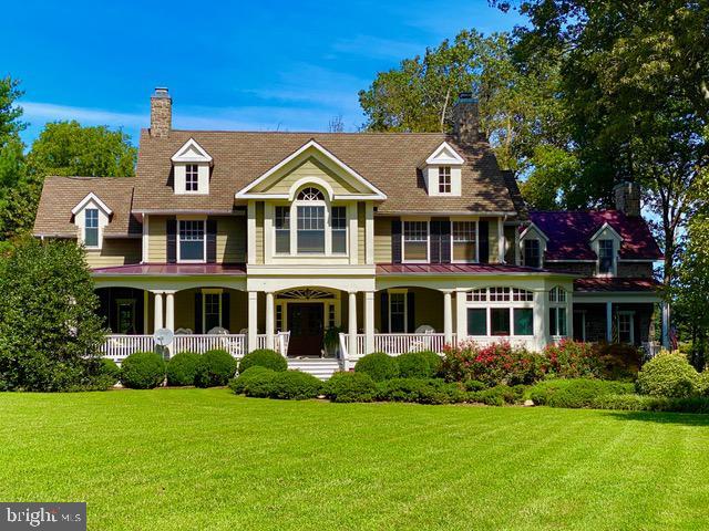 view of front of house with a porch, a chimney, and a front lawn