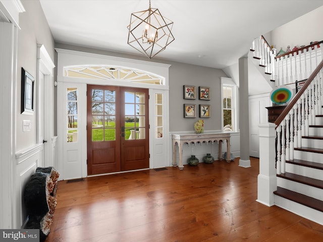 entryway with an inviting chandelier, stairs, and hardwood / wood-style floors