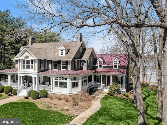 back of property with a chimney, a porch, a standing seam roof, a yard, and metal roof