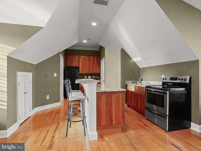 kitchen with a center island, light wood finished floors, a kitchen breakfast bar, and stainless steel range with electric cooktop