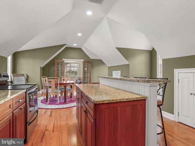 kitchen featuring light wood-style floors, a kitchen breakfast bar, vaulted ceiling, and electric stove