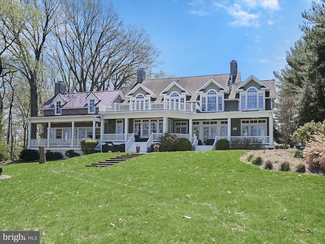 view of front of home featuring a chimney, covered porch, and a front yard