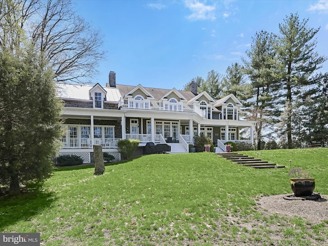 back of property featuring a porch, a lawn, and a chimney