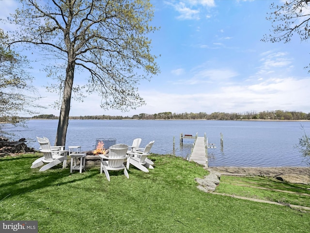 dock area with a water view, an outdoor fire pit, and a lawn