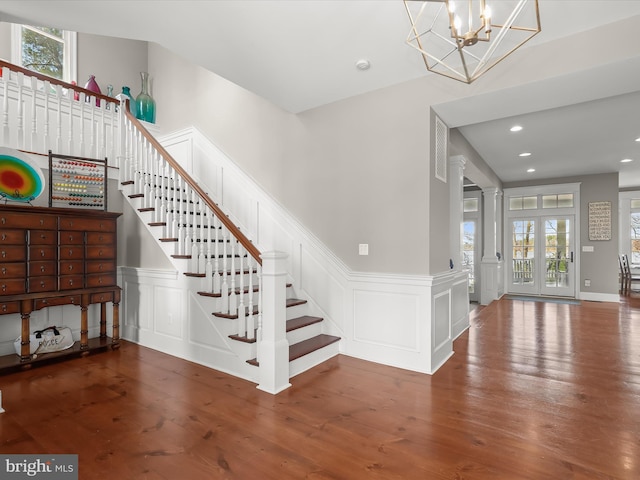 stairs featuring wood finished floors, a decorative wall, and a healthy amount of sunlight