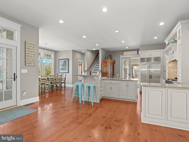 kitchen with built in refrigerator, light wood-style flooring, and white cabinetry