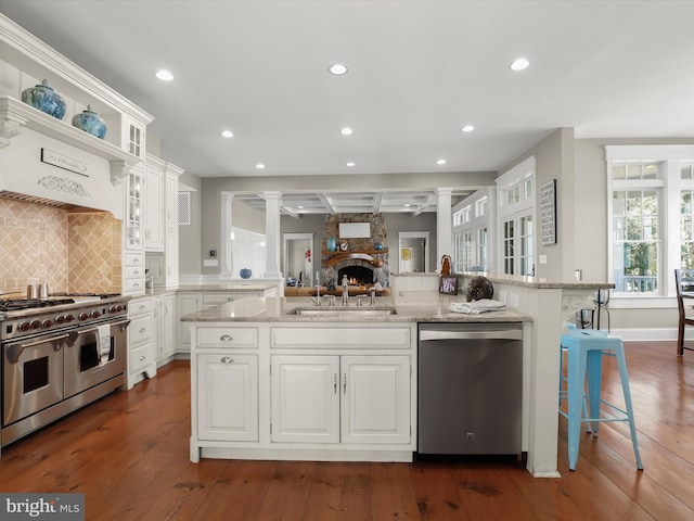 kitchen with a sink, appliances with stainless steel finishes, ornate columns, and dark wood finished floors
