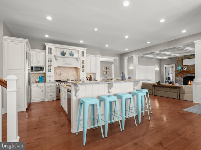 kitchen featuring wood-type flooring, white cabinets, backsplash, and built in appliances