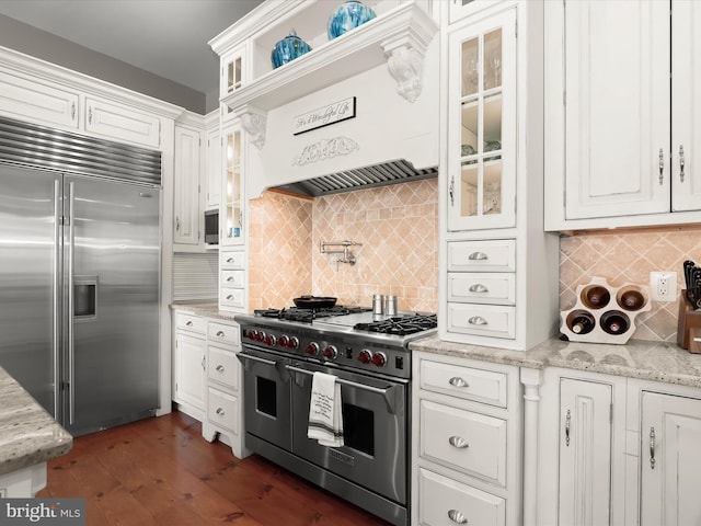 kitchen with glass insert cabinets, high end appliances, white cabinetry, decorative backsplash, and dark wood-style floors