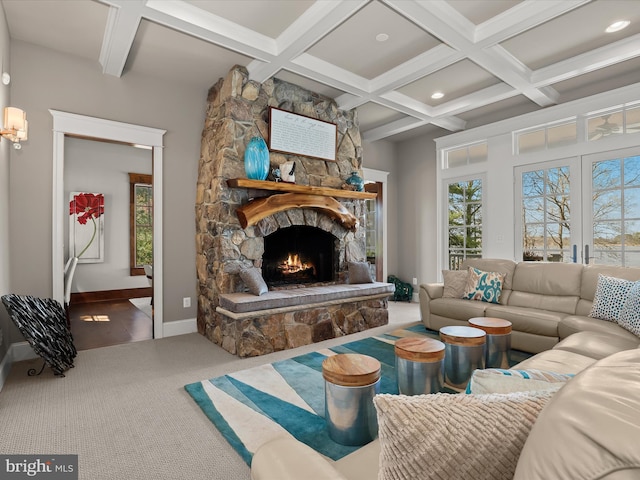 carpeted living area featuring a stone fireplace, baseboards, beam ceiling, and coffered ceiling