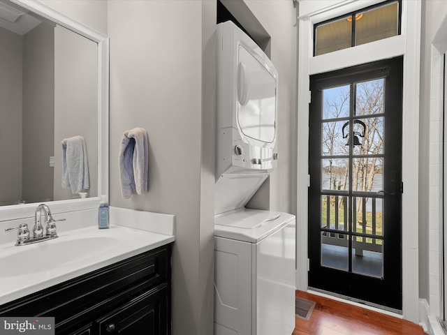 washroom with visible vents, stacked washer / drying machine, a sink, and laundry area