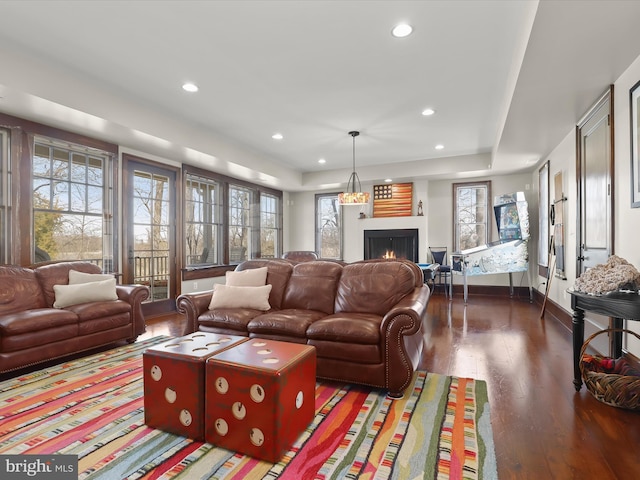 living area featuring a wealth of natural light, wood finished floors, and a lit fireplace