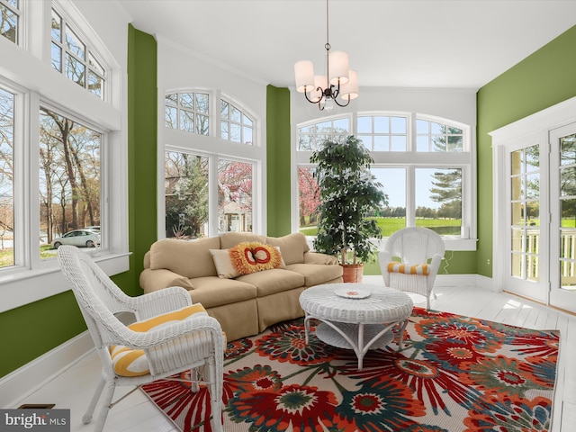 sunroom with french doors, a notable chandelier, and baseboards