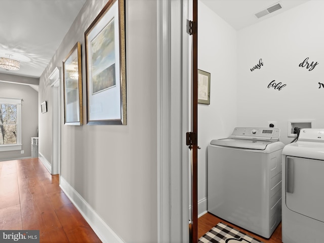 laundry room with laundry area, separate washer and dryer, wood finished floors, and visible vents
