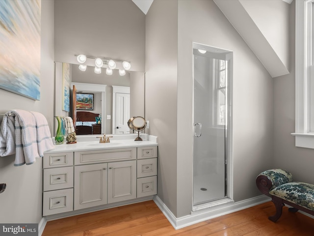 ensuite bathroom featuring a stall shower, wood finished floors, ensuite bathroom, and baseboards
