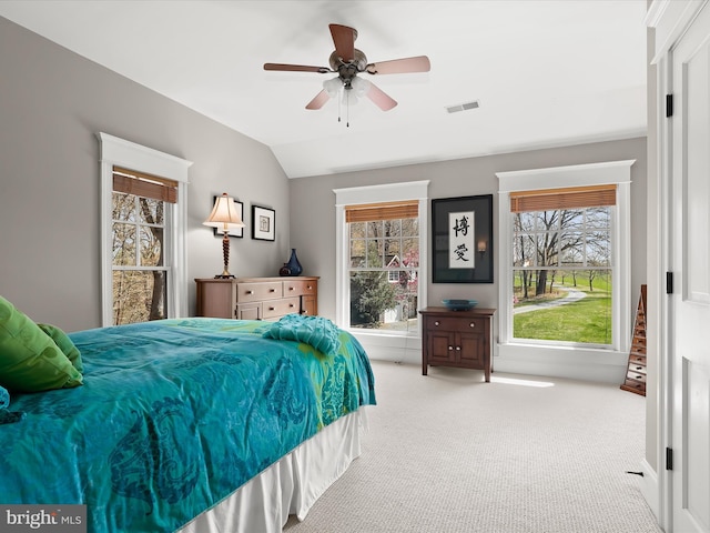 carpeted bedroom featuring ceiling fan, vaulted ceiling, and visible vents