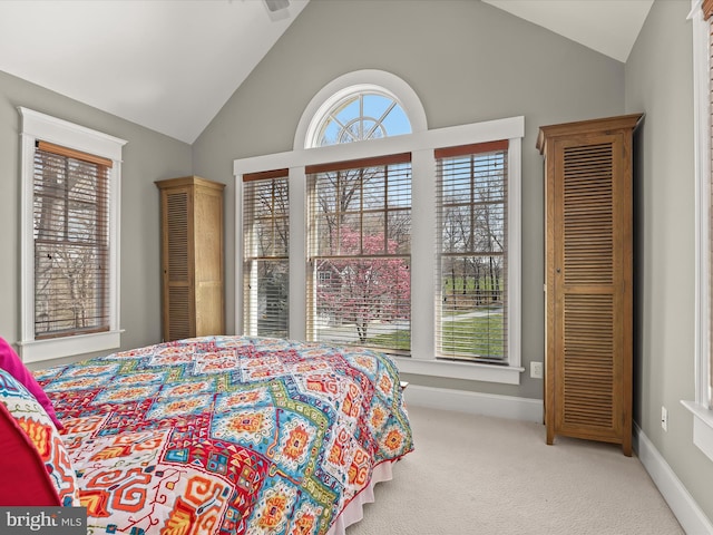 carpeted bedroom featuring baseboards, multiple windows, and lofted ceiling