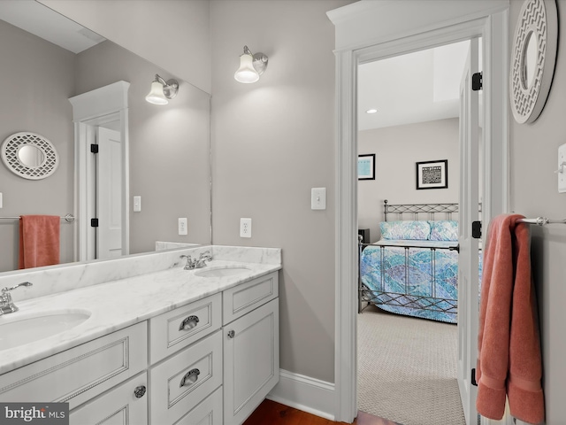 full bathroom featuring double vanity, ensuite bathroom, a sink, and baseboards