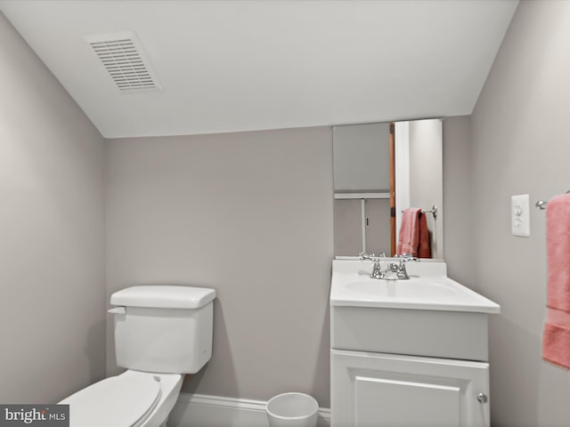 half bath with toilet, vanity, baseboards, and visible vents