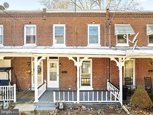 townhome / multi-family property featuring covered porch and brick siding