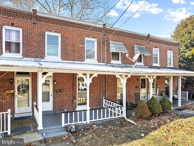 view of property with a porch and brick siding