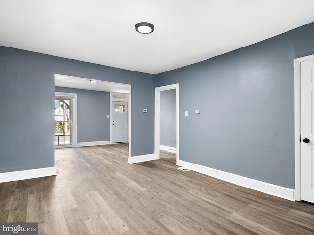 empty room featuring wood finished floors, visible vents, and baseboards