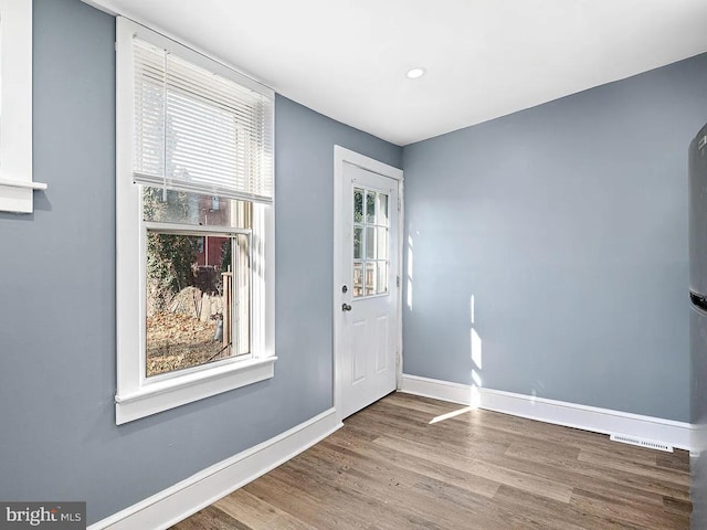 foyer with a healthy amount of sunlight, visible vents, baseboards, and wood finished floors