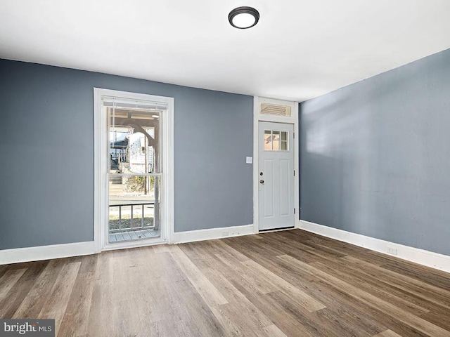 entrance foyer with visible vents, baseboards, a wealth of natural light, and wood finished floors