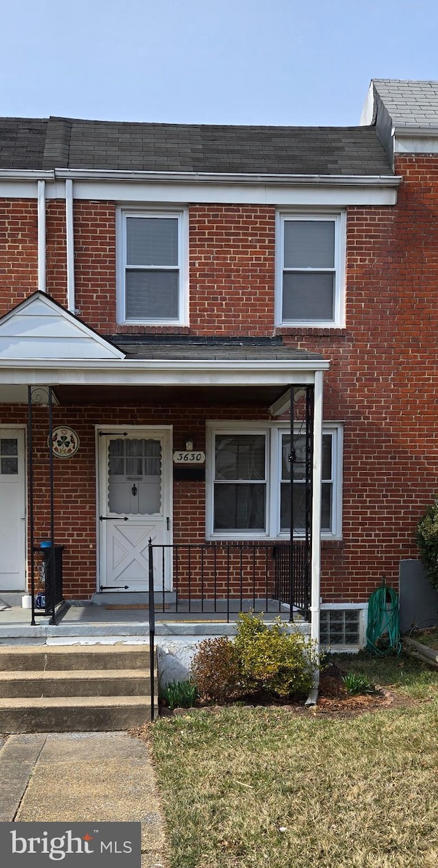 townhome / multi-family property featuring brick siding and covered porch