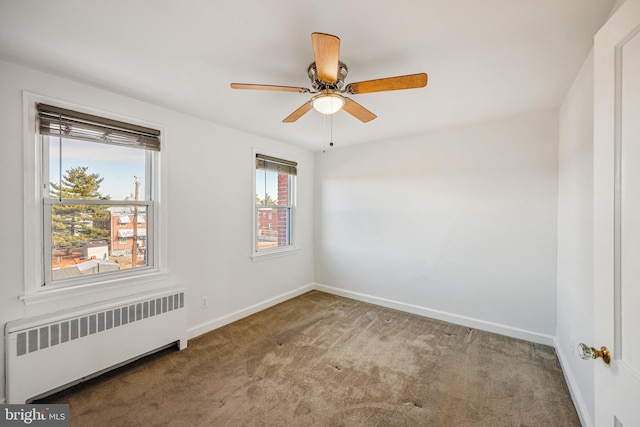 carpeted spare room featuring ceiling fan, radiator heating unit, and baseboards