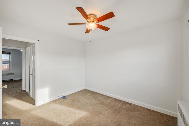 carpeted empty room featuring radiator, a ceiling fan, and baseboards