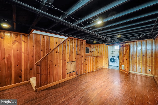 finished basement with wooden walls, baseboards, washer and clothes dryer, stairway, and wood finished floors