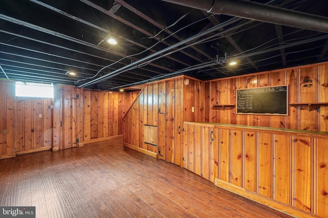 below grade area featuring hardwood / wood-style floors and wood walls