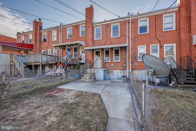 back of property with brick siding, a chimney, and fence