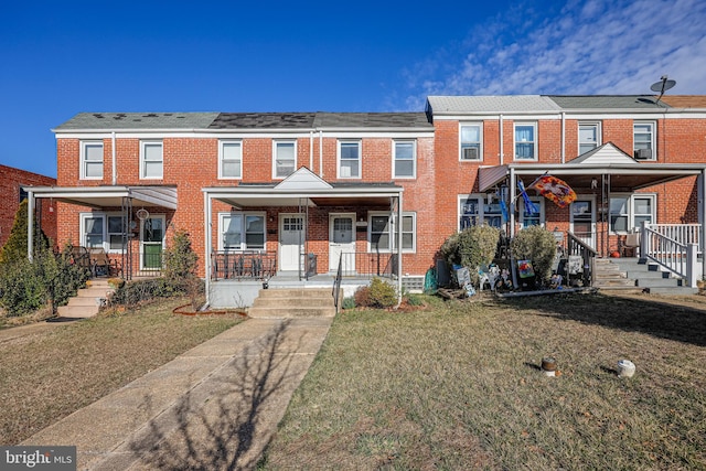 view of property with brick siding, covered porch, and a front yard