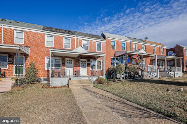 view of property featuring brick siding, a residential view, a porch, and a front lawn