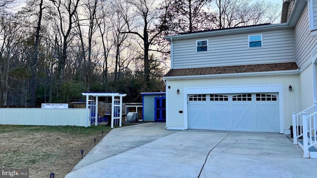 garage featuring driveway and fence