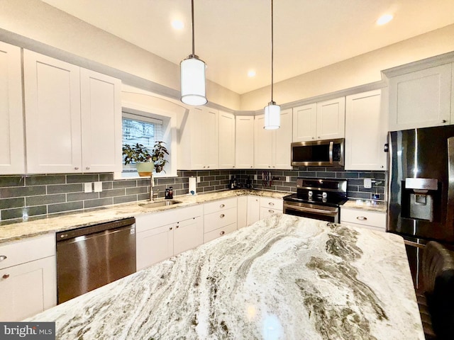 kitchen with backsplash, appliances with stainless steel finishes, hanging light fixtures, white cabinetry, and a sink