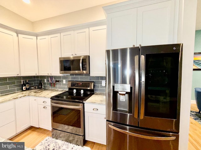 kitchen with light stone countertops, light wood-style floors, backsplash, and stainless steel appliances