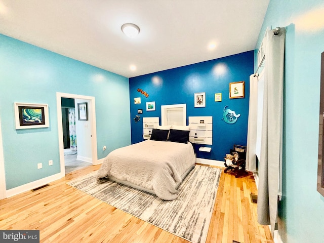 bedroom with visible vents, baseboards, and wood finished floors